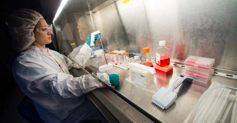 Researcher with cell culture products under laboratory hood, pipetting