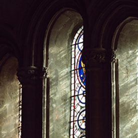 Sun shines through three oval stained glass windows in cathedral