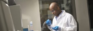 Man wearing white lab coat, goggles in laboratory setting