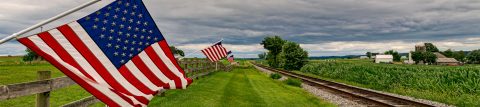 American flag waving along side a railroad